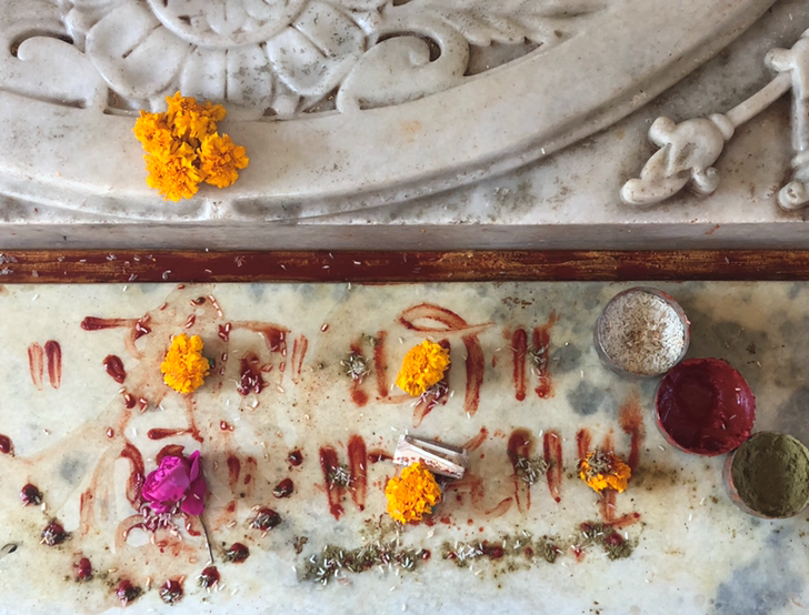Yellow marigolds and pink flowers spread with spices on a marble table